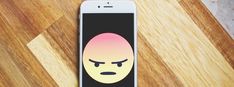 phone with angry emoji on screen