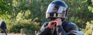 Motorcyclist putting on a helmet, which could be helpful if there is a Fishers motorcycle claim later on